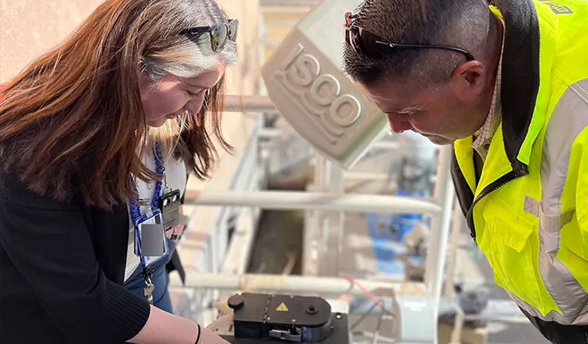 Sarah Holcomb and Randy Vigil check a device that collects wastewater samples