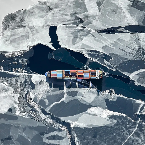 Aerial view of a cargo ship navigating through fractured sea ice.