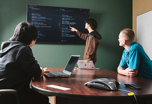 Jason Lee, Qing Zheng, and David Bonni sitting at a desk looking at a monitor.