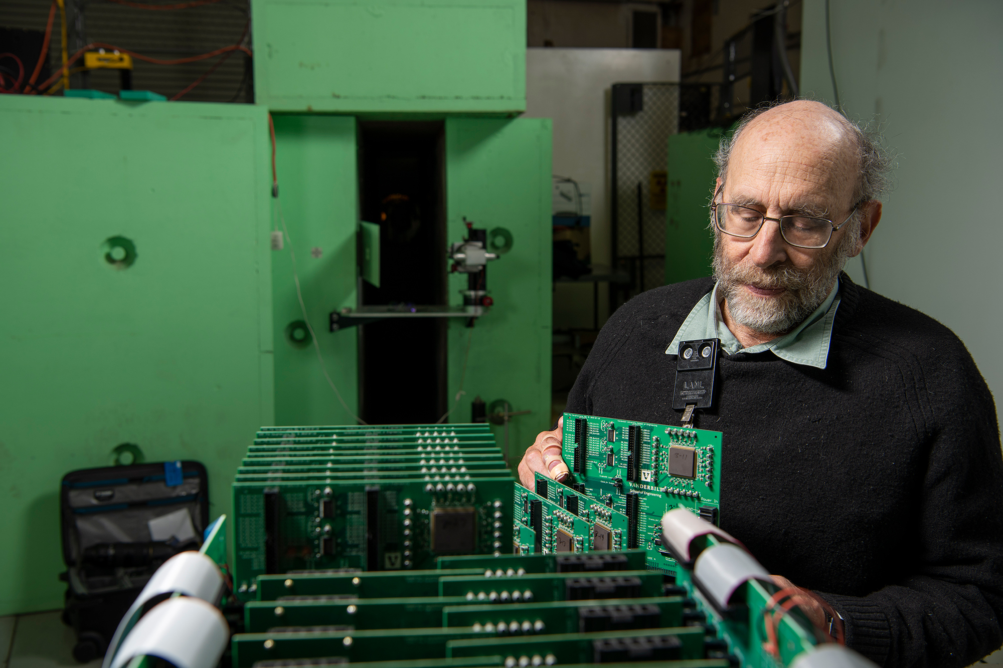 Photograph of physicist Steve Wender lining up many circuit boards in a row.