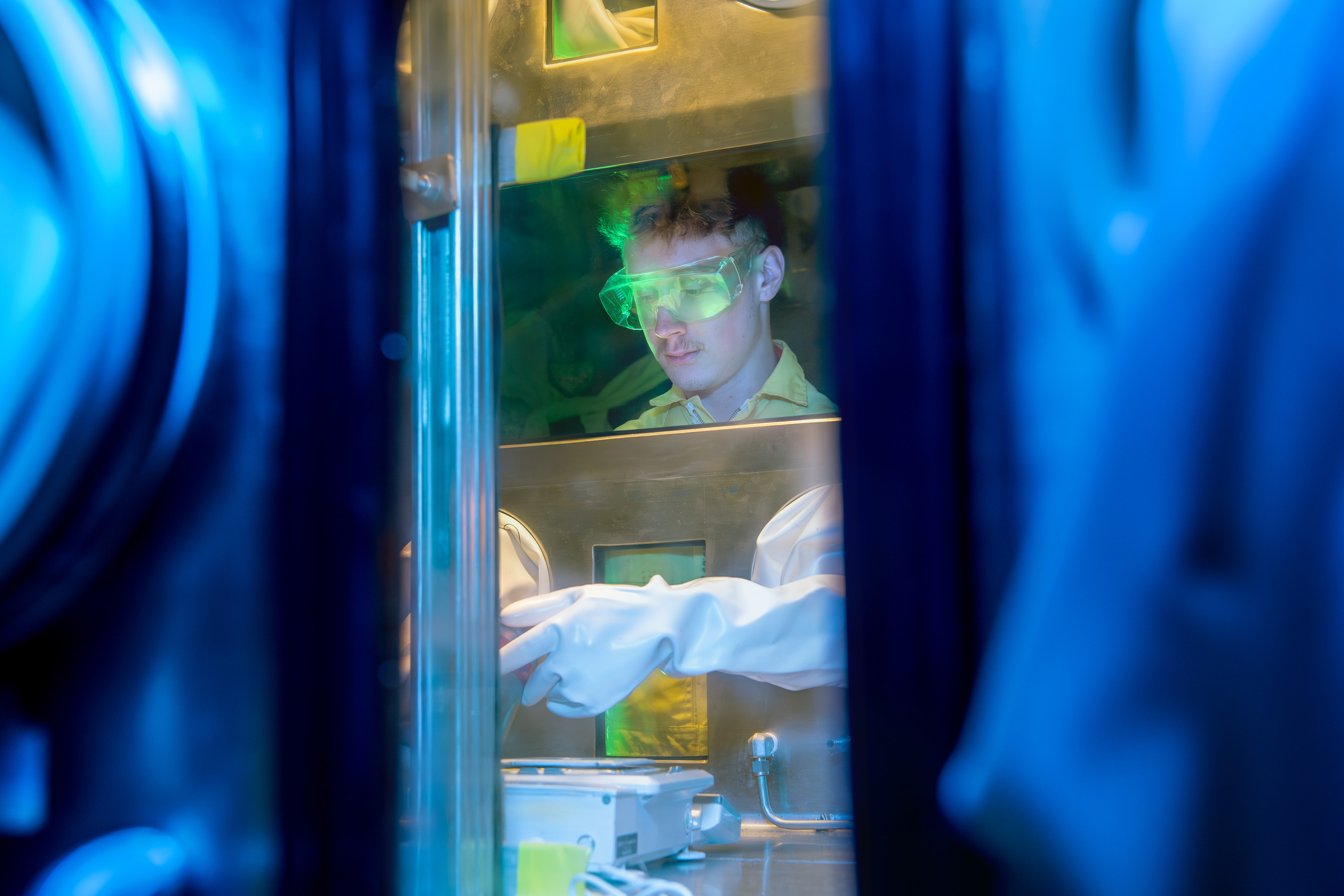 A Pit Production worker moves something within a glovebox.