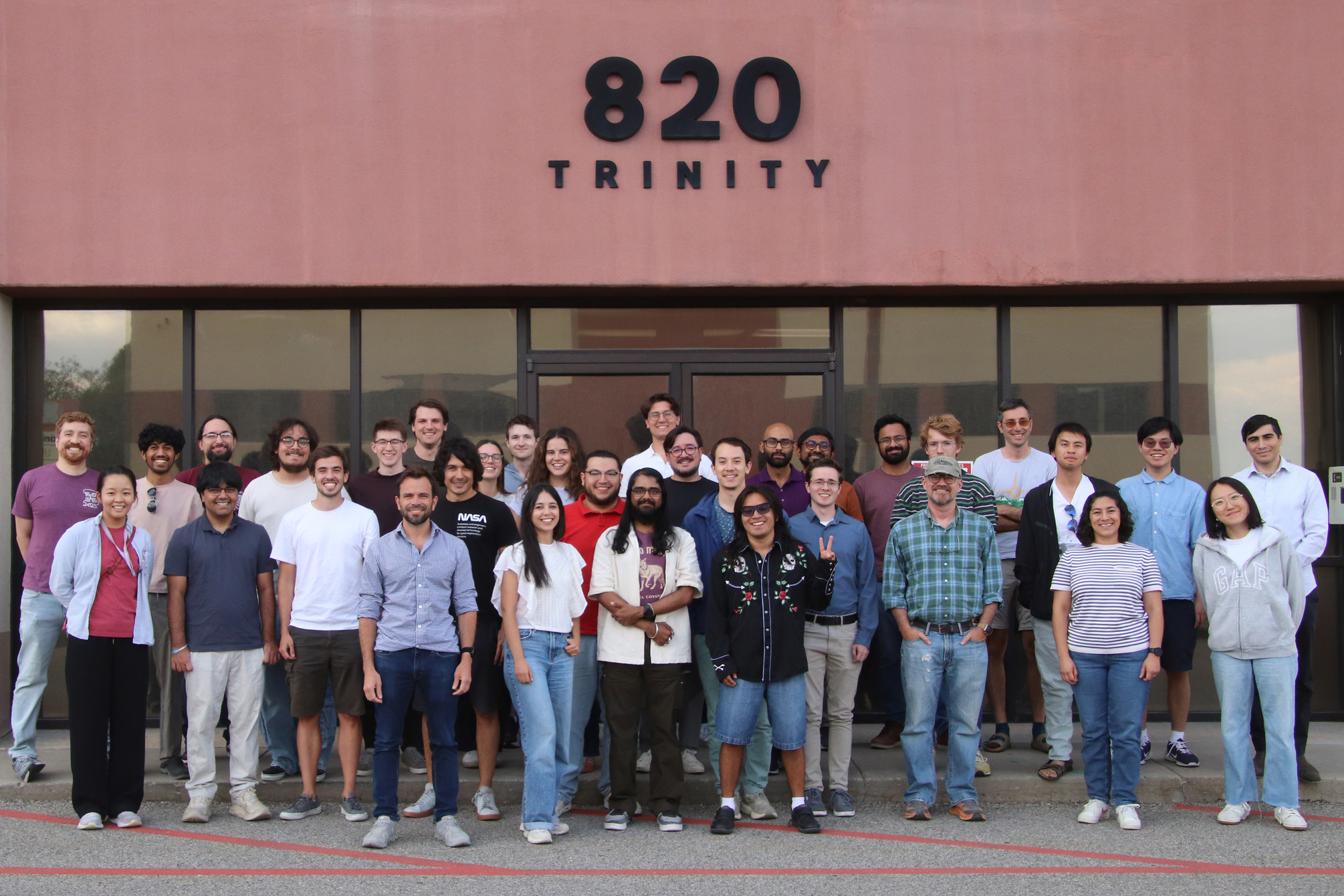 A group poses outside a building marked “820 Trinity.”