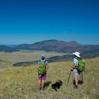 Scenic view of New Mexico hills with two hikers standing in the foreground facing the hills