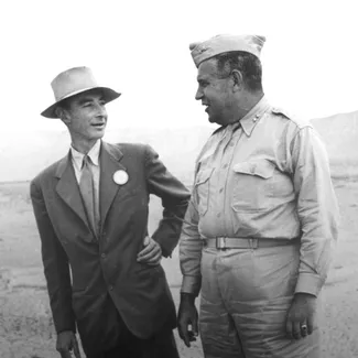 Black and white photo of Oppenheimer talking to General Groves